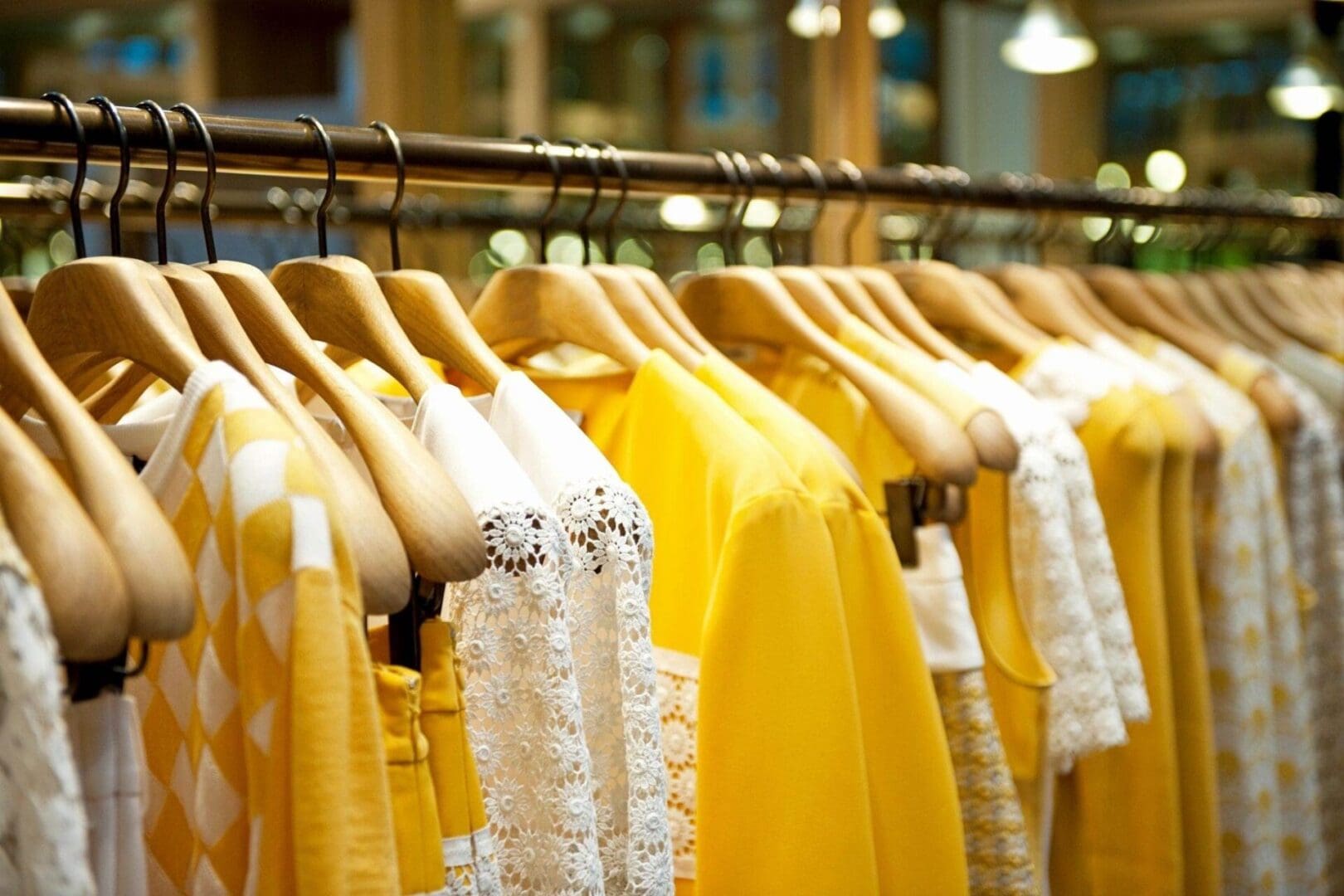 Yellow fashionable, stylish clothes on hangers in stores